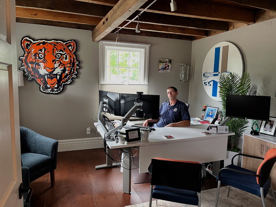 Matt Bowden at his desk in his office with a custom Classic Tigers tiger head on one wall and a retro Classic Lions circle on the other