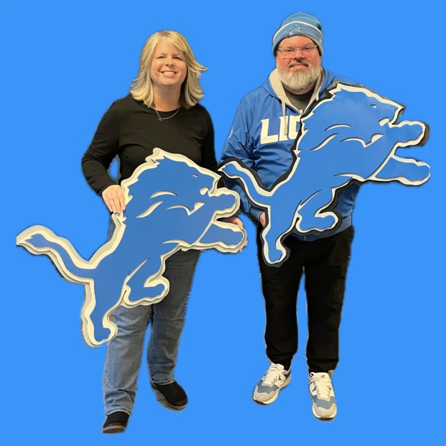 Two customers holding custom Detroit Lions logo cutouts