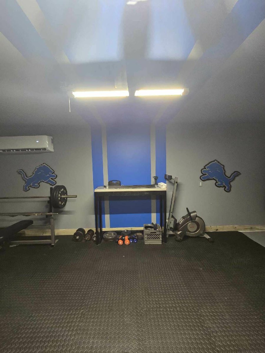 Two custom Detroit Lions logo cutouts in a home gym with blue stripe wall
