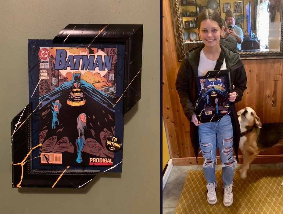 Hand-embellished Batman Prodigal comic cover in a splatter-painted black frame with an I'm Batman button, and held by a customer