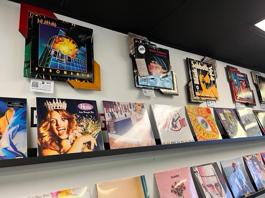 Hand-embellished Def Leppard Pyromania, Black Sabbath Paranoid and Black Sabbath Vol. 4 album pieces on a record shop wall above rows of vinyl