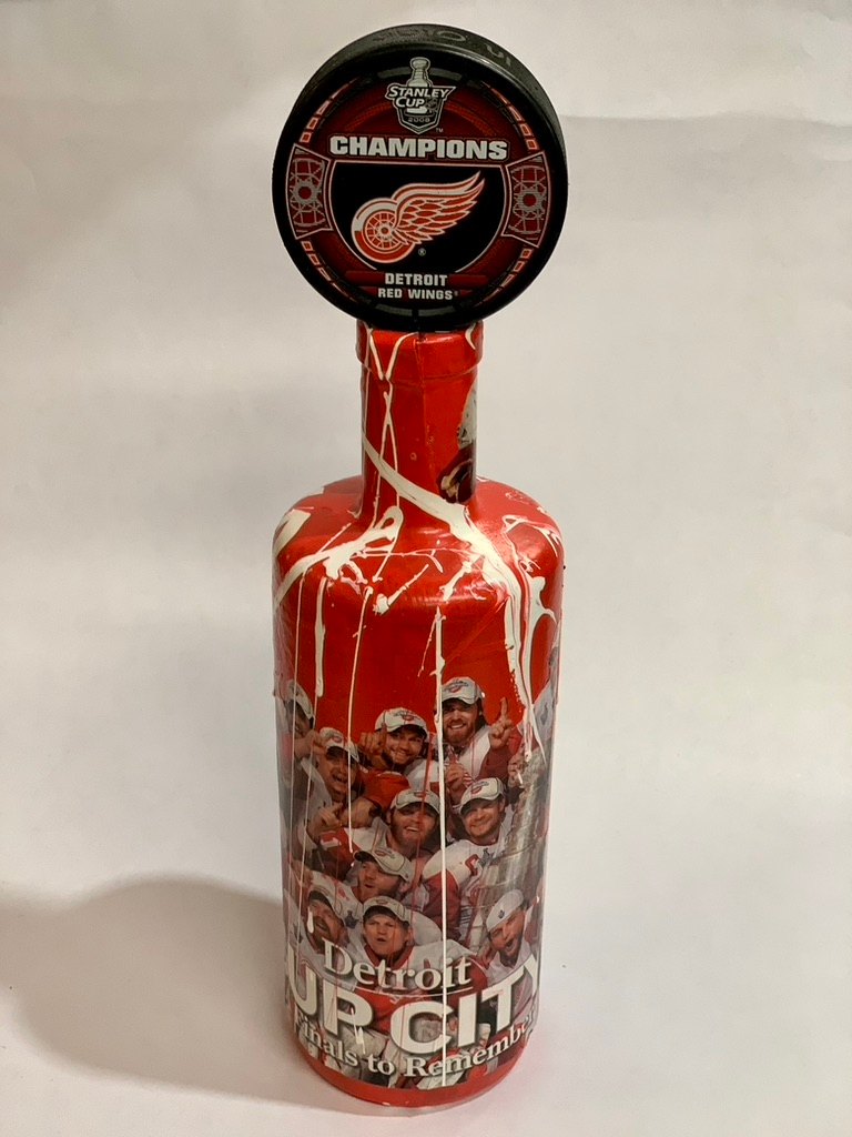 Hand-painted red Detroit Red Wings Cup City bottle topped with a Stanley Cup Champions puck