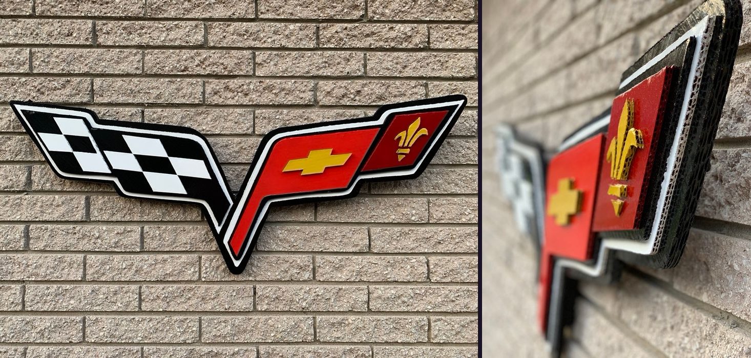 Custom Corvette crossed flags emblem cutout with checkered flag, red Chevy bowtie flag and gold fleur-de-lis: front view on brick and an angled close-up showing the layers