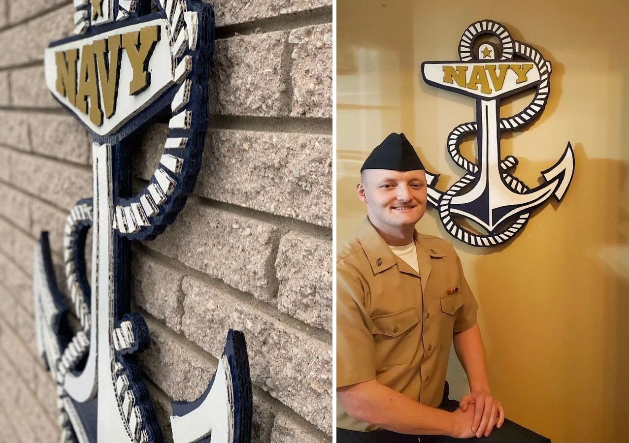 Custom Navy anchor cutout in navy, white and gold: an angled close-up on a brick wall showing the layered cardboard rope, and the anchor on a wall behind a Navy sailor in uniform