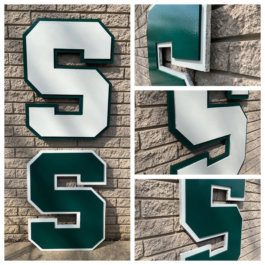 Custom white and green Michigan State block S cutouts on a brick wall, front view and close-up angles