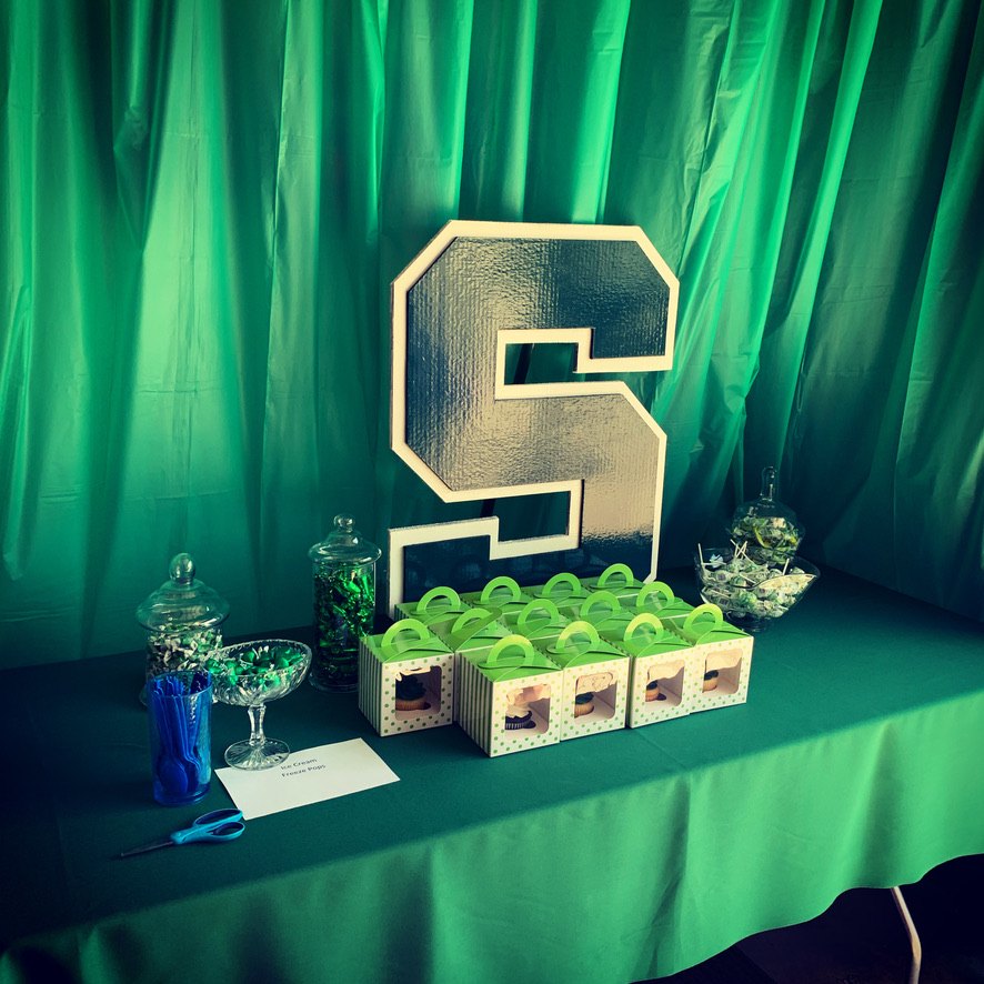 Custom Michigan State block S cutout as a graduation party centerpiece on a dessert table with green decor
