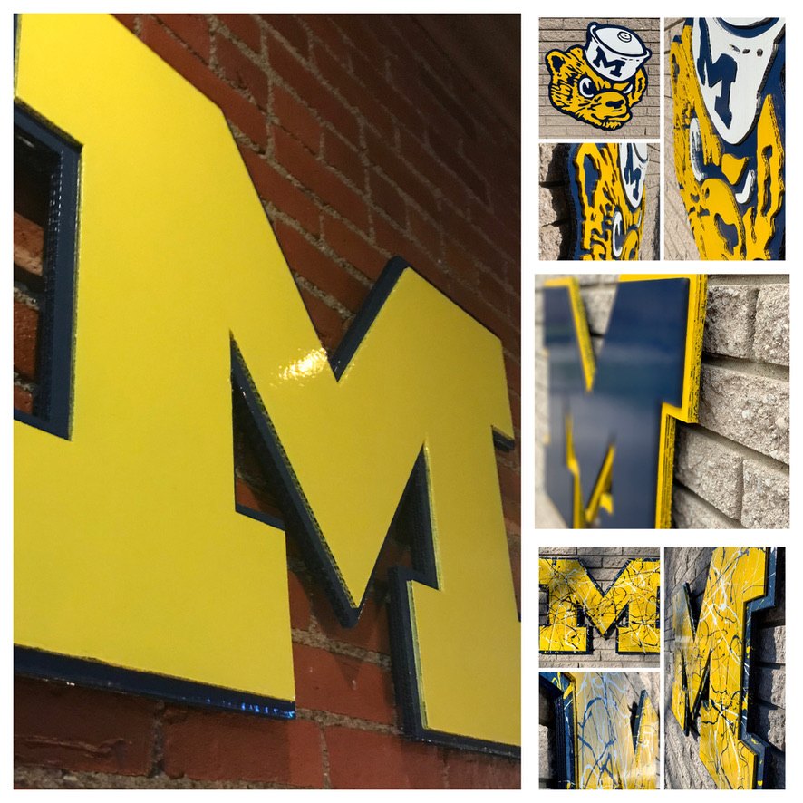 Collage of custom Michigan block M cutouts in maize and blue on brick, including a splatter-painted M and the vintage Wolverine mascot