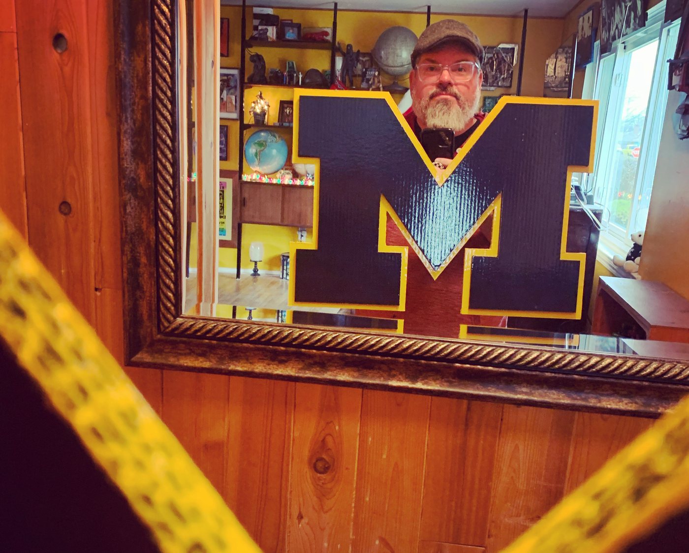 Navy Michigan block M with maize trim, held up in a mirror