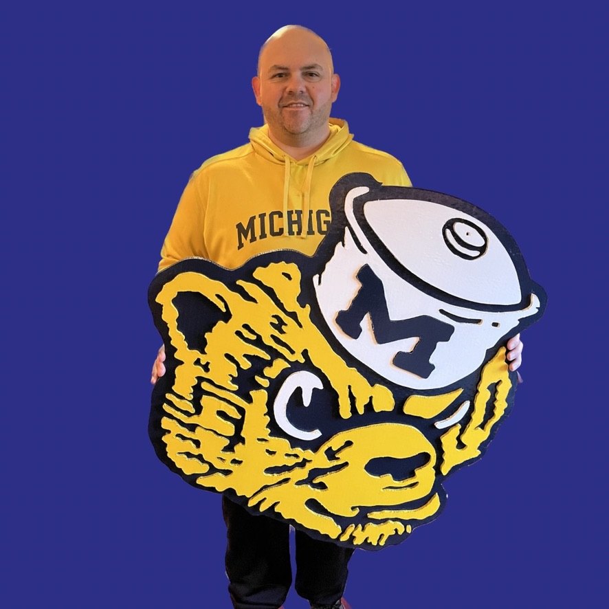 Jeremy holding the custom Classic Wolverine mascot cutout against a blue backdrop