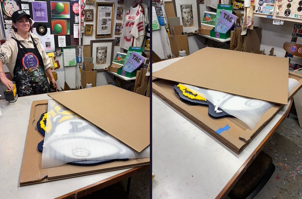 Studio assistant Allison packing a custom Classic Wolverine cutout in foam and cardboard for shipping in The Art Jar workshop