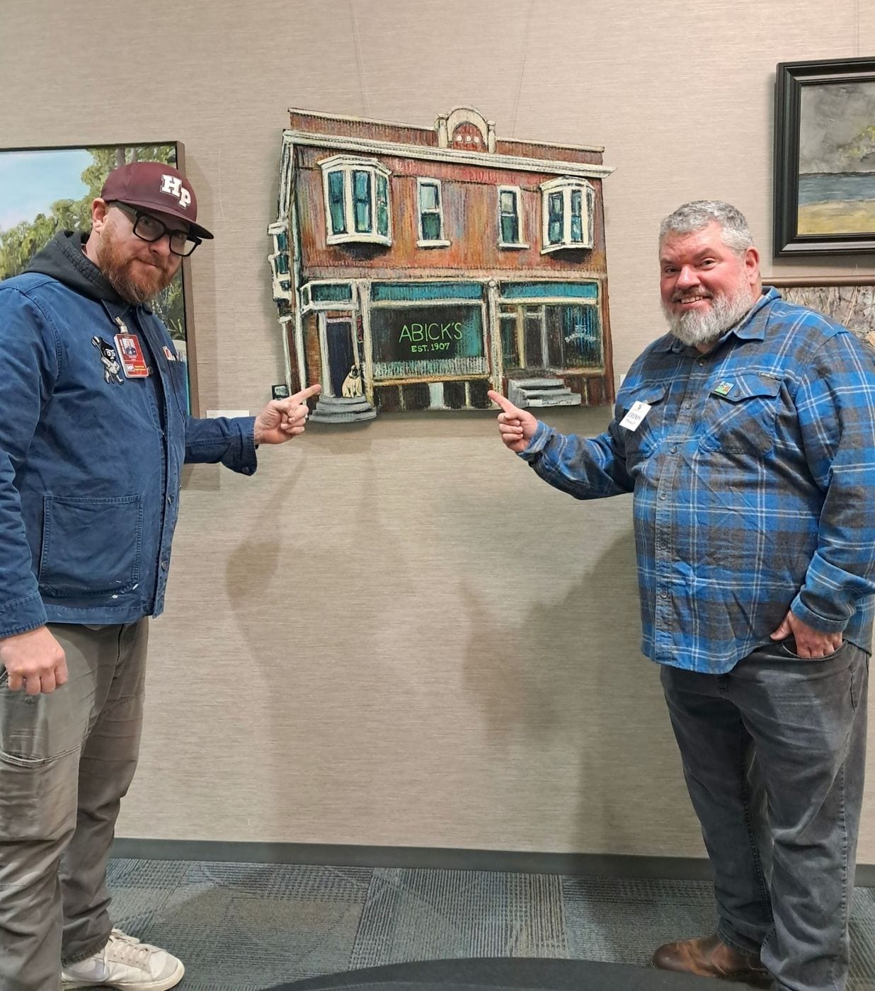 Johnny Hicks and Jeremy Allen Rheault pointing at Abick’s Shadow on the gallery wall