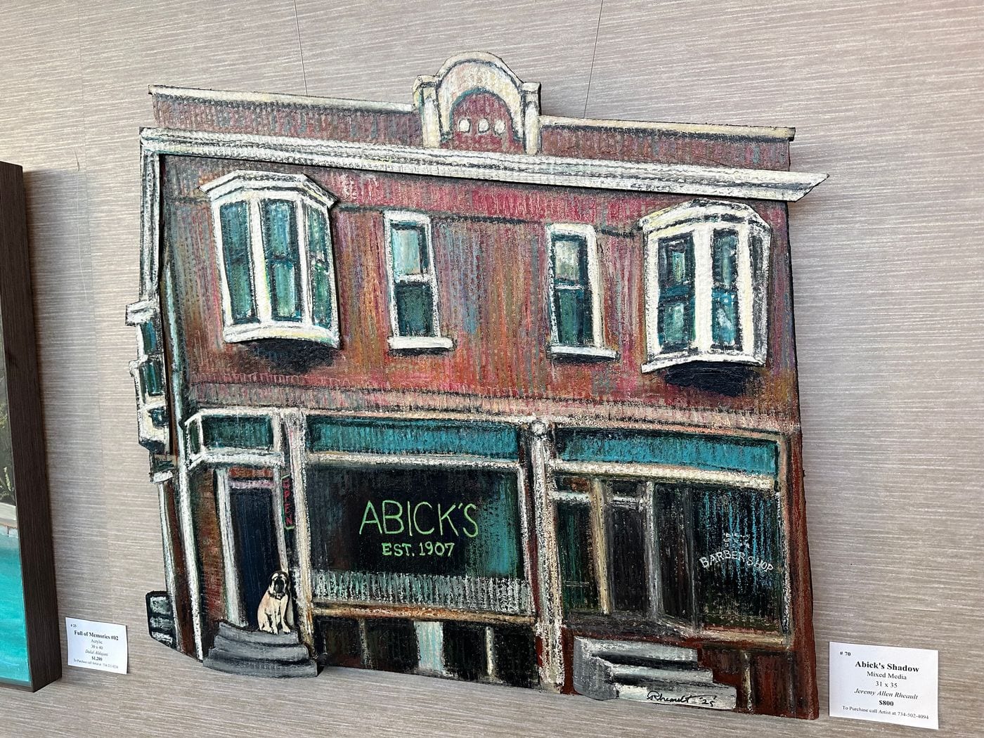 Abick’s Shadow, a hand-cut, hand-painted storefront of Abick’s, on the gallery wall with its label