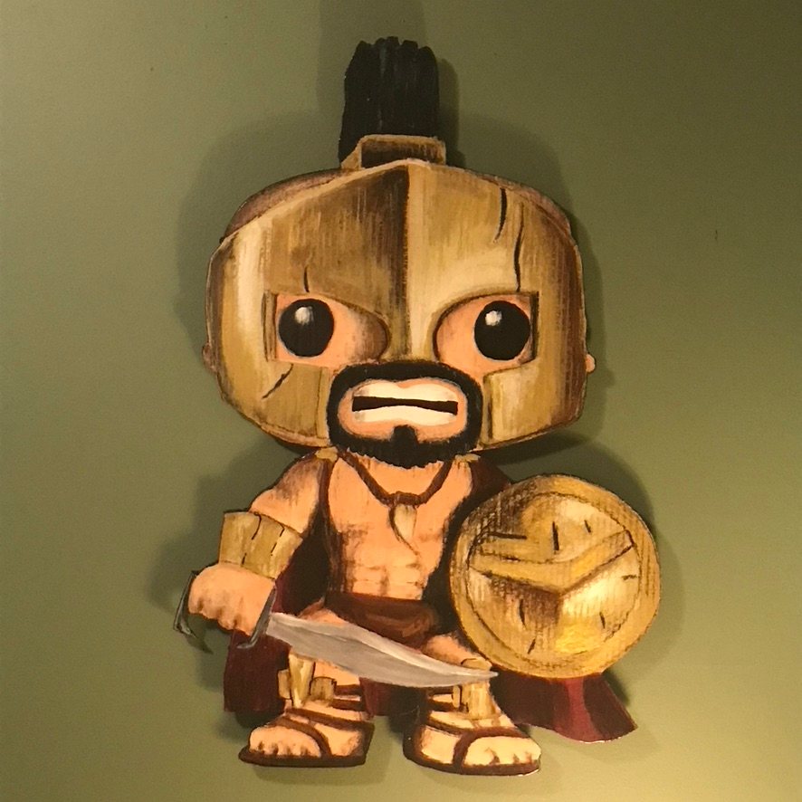 Hand-cut and hand-painted Funko Pop style Spartan warrior in a bronze helmet with a black crest, holding a curved sword and a round shield, on a green wall