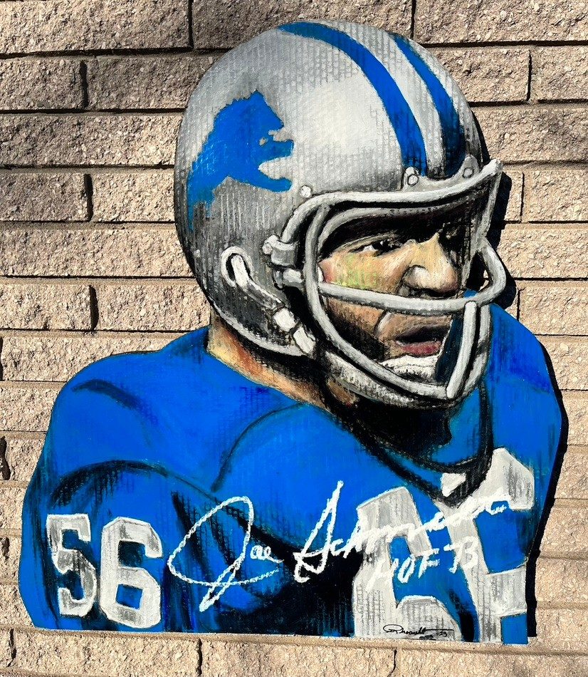 Hand-cut and hand-painted portrait of a Detroit Lions linebacker, number 56, in a silver helmet and blue jersey, signed Joe Schmidt HOF 73, on a brick wall