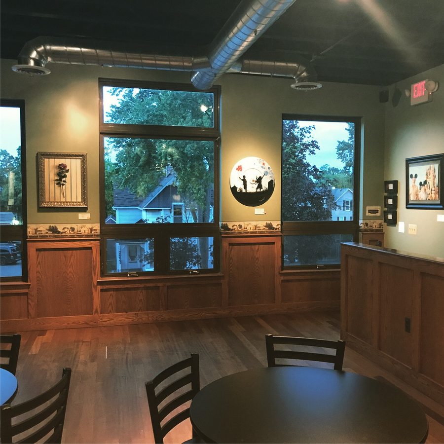 Framed pieces and a round black-and-white piece hung between the tall windows of the gallery dining room