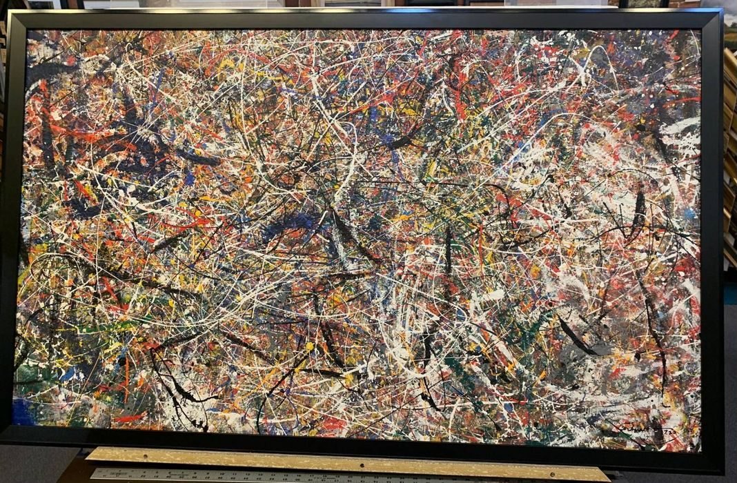 Journey, a large multicolor splatter painting in a black Frame Works frame, resting on the framing table