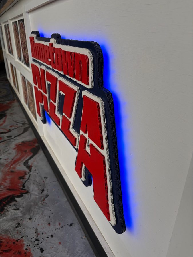 Angled close-up of the Hometown Pizza sign showing the stacked layers and blue LED backlight