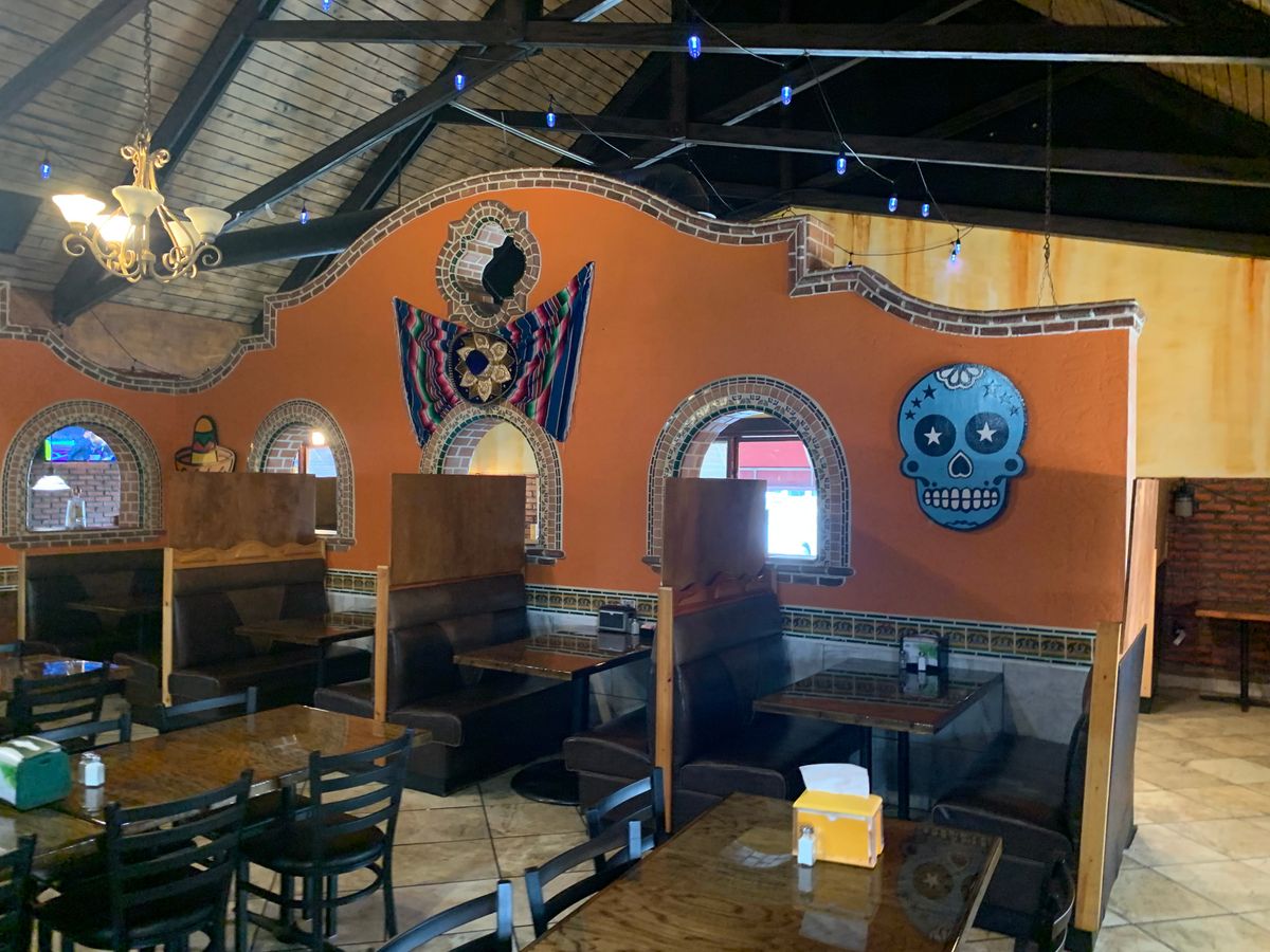 Dining room at Los Amigos with the blue sugar skull on the orange wall above the booths