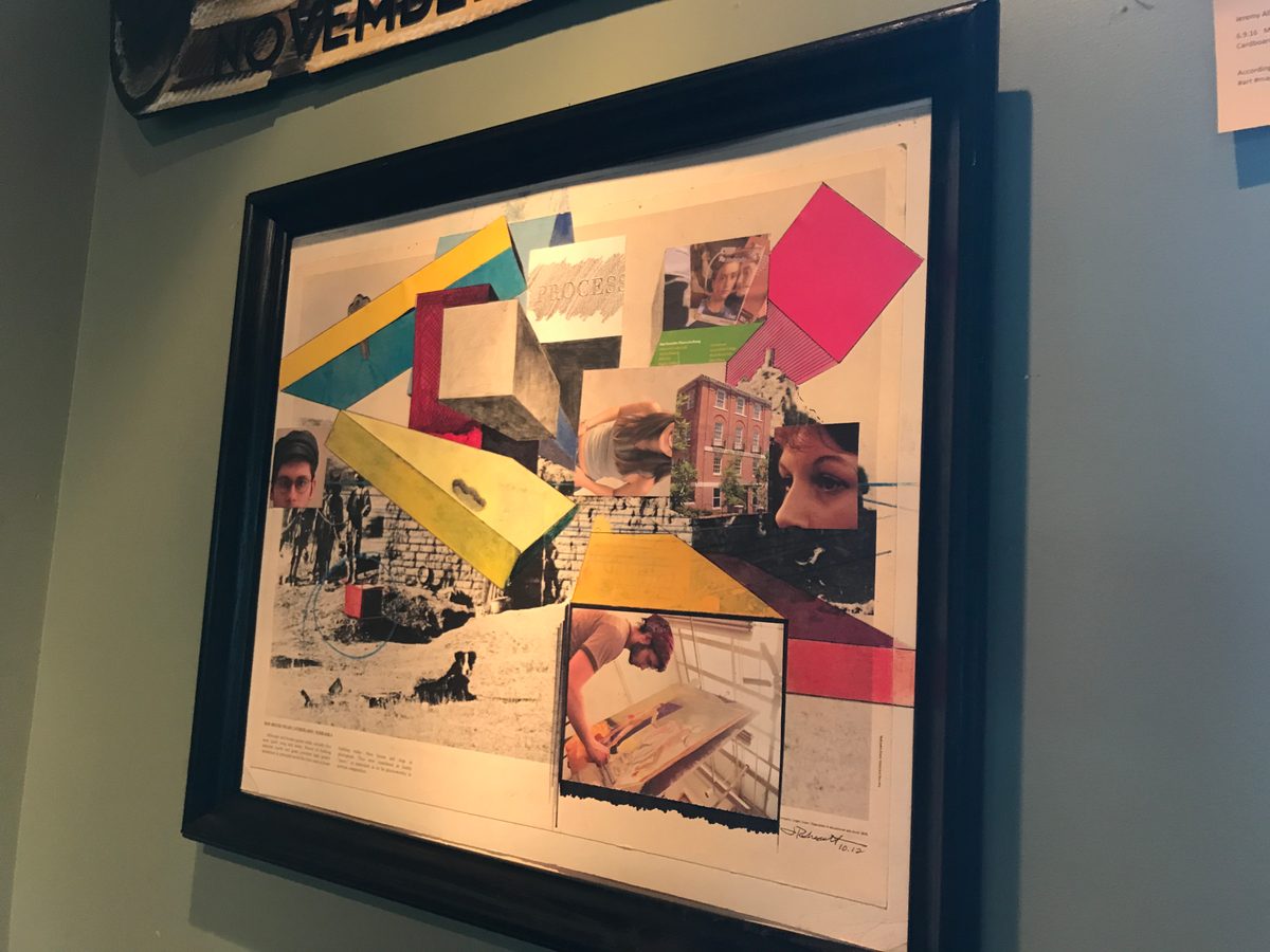 Framed mixed media collage with colorful geometric shapes and a pink square, hung on the wall