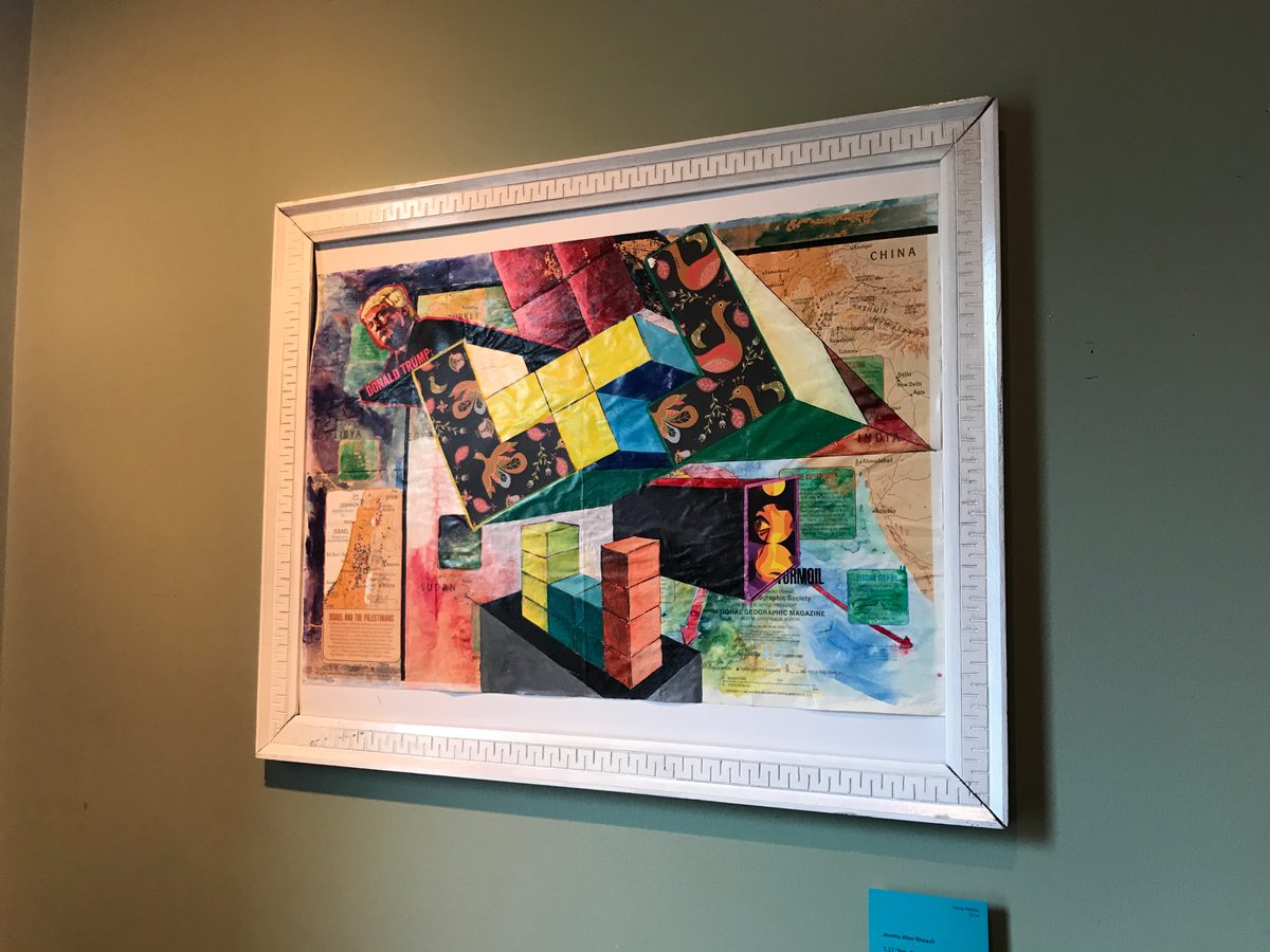 Framed colorful geometric collage in a white frame hung on a gray wall