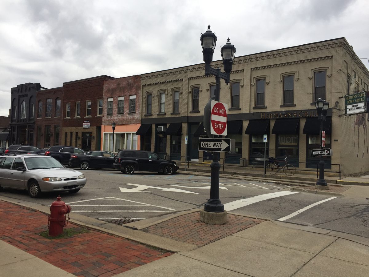 Street corner in Plymouth’s Old Village with a lamp post, a row of brick storefronts and a one-way sign