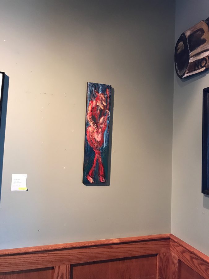 A tall painting of a red figure hung on a gray wall above the wood wainscot at Liberty Street Brewing Company