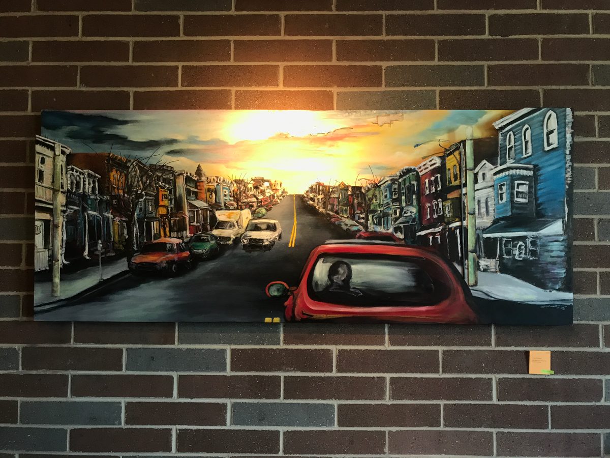 Large painting of a city street at sunset with a red car in the foreground, hung on a brick wall at Liberty Street Brewing Company