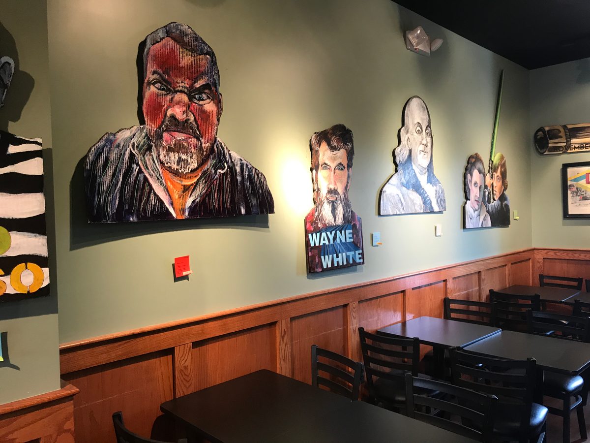 Wall of hand-cut cardboard portraits including a bearded man, Wayne White and Ben Franklin at Liberty Street Brewing Company