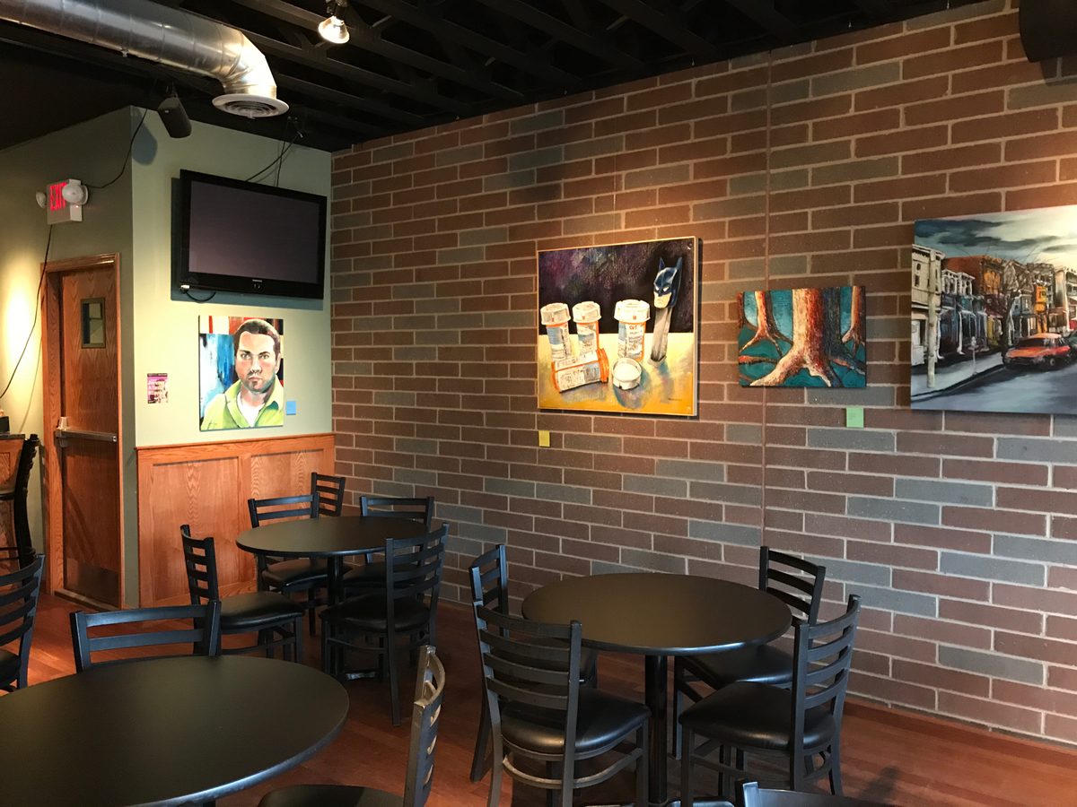 Corner of the Up Stairs Hall with the Pills and Pez painting, the tree roots painting and Street Sunset hung on the brick wall