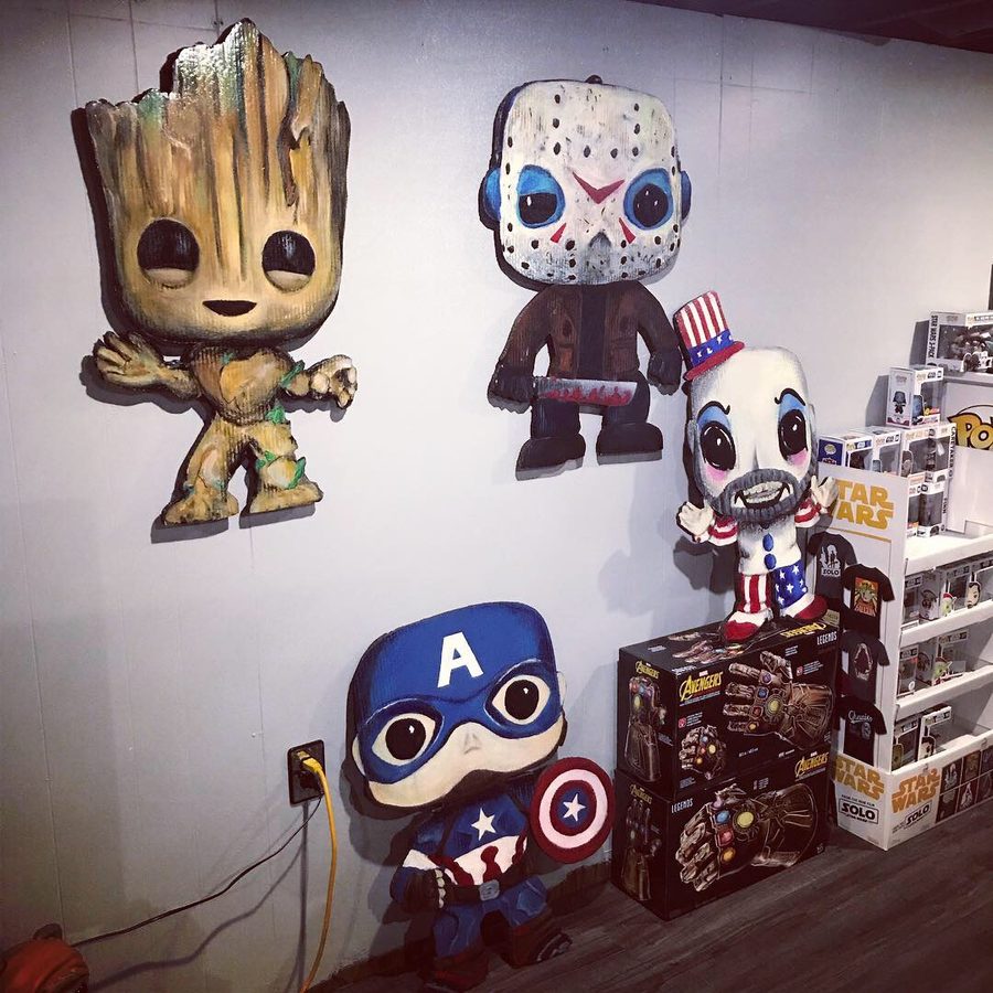 Groot, Jason Voorhees, Captain America and Captain Spaulding Funko-style cutouts on a white wall above boxed collectibles