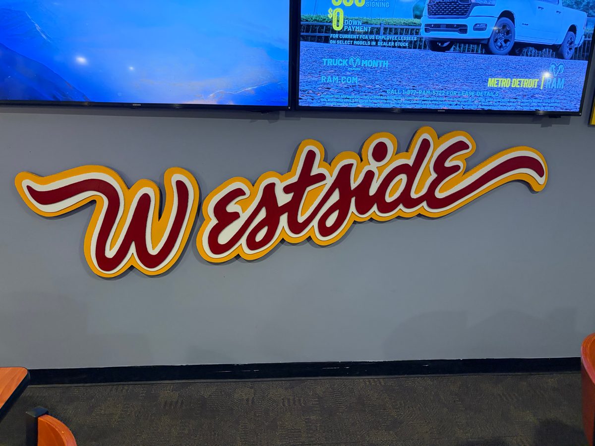 The red and yellow Westside script sign under two TVs