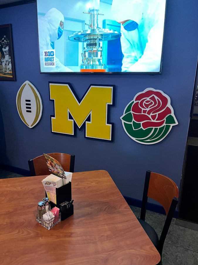 The Michigan M, football and rose on the wall above a table