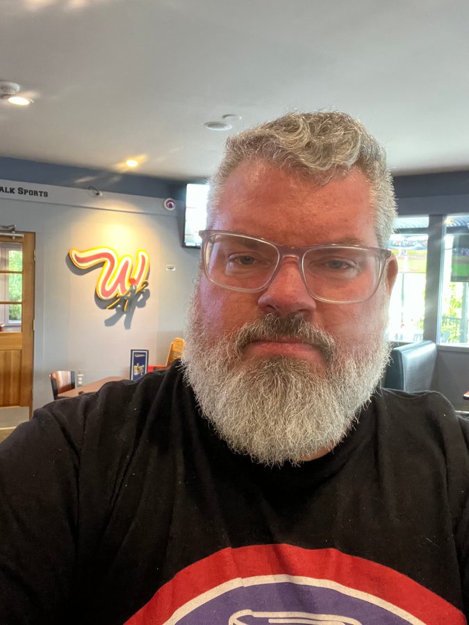 Jeremy Rheault taking a selfie in the dining room with the W logo on the wall behind