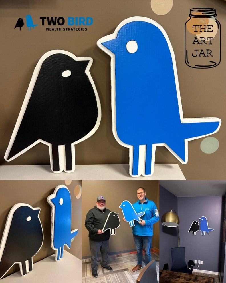 Collage of the black and blue Two Bird Wealth Strategies logo birds cut out in cardboard, close up, held by Jeremy Rheault and Matt Bowden, and hung on a purple office wall