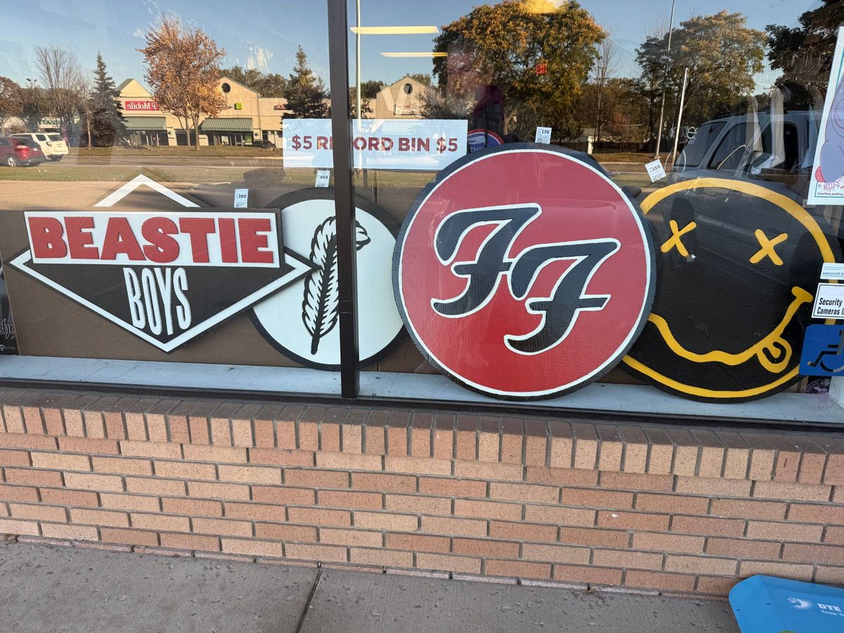 Close view of the hand-cut Beastie Boys, Led Zeppelin Robert Plant symbol feather, Foo Fighters FF and Nirvana smiley logos sitting in the shop window above the brick sill