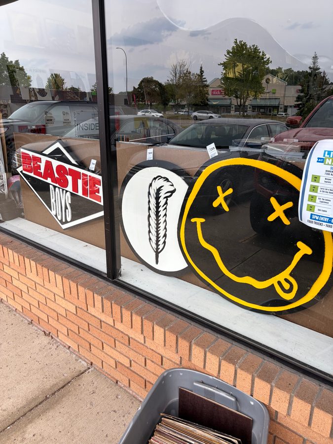 Hand-cut Beastie Boys and Nirvana smiley logo pieces in the front window of Vinyl People Records
