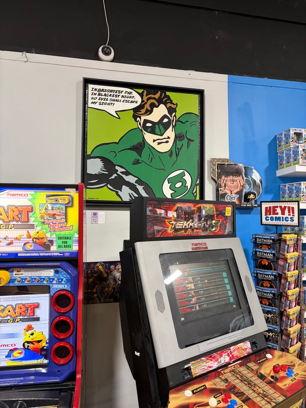 Green Lantern hanging above an arcade cabinet inside State of Comics